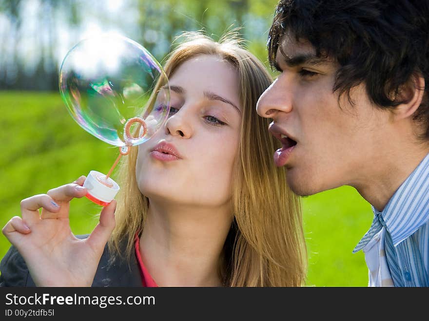 Attractive multi-racial couple in love blowing bubbles on nature