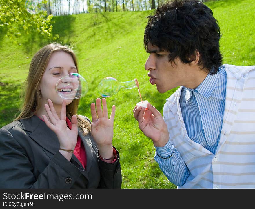 Attractive multi-racial couple in love blowing bubbles on nature