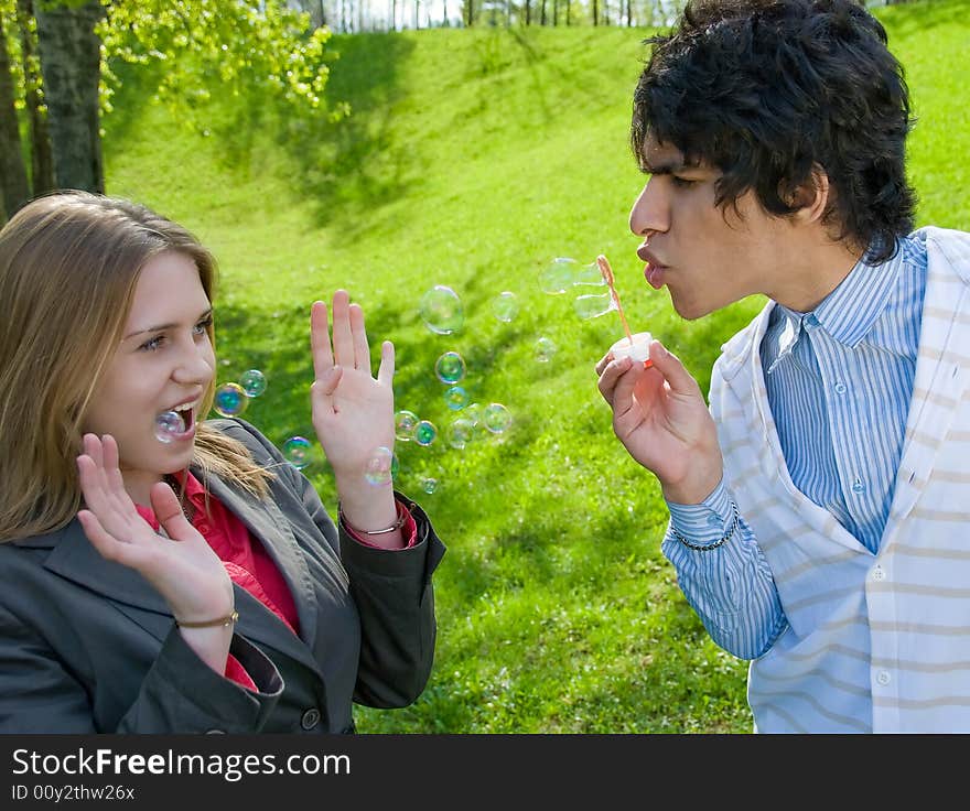 Attractive multi-racial couple in love blowing bubbles on nature