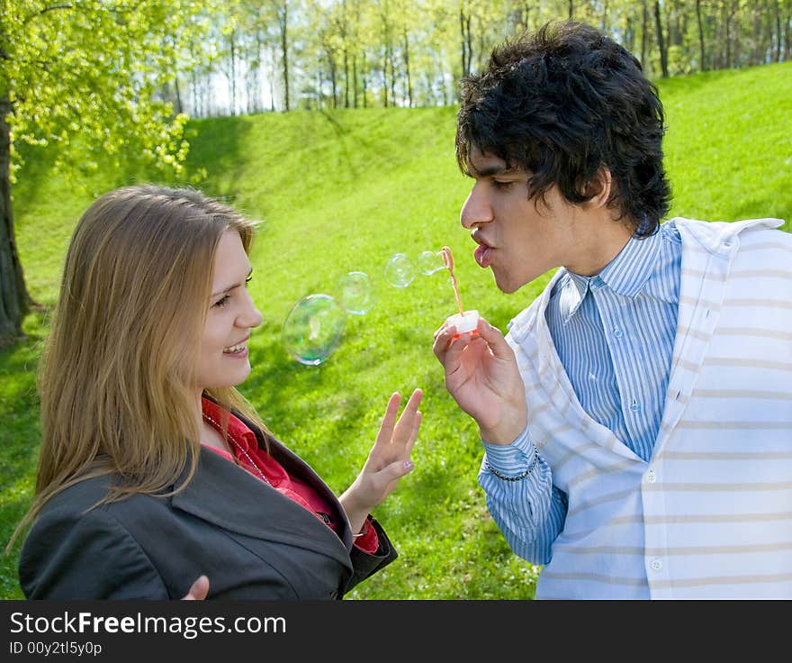 Attractive multi-racial couple in love blowing bubbles on nature