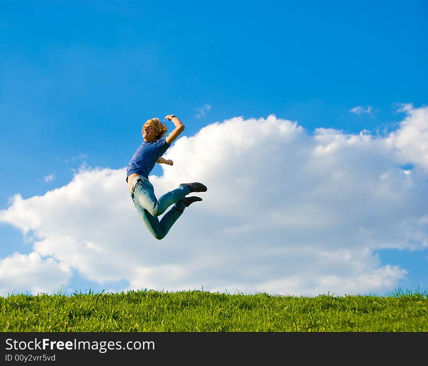 Happy teenager jumping over green grass field.