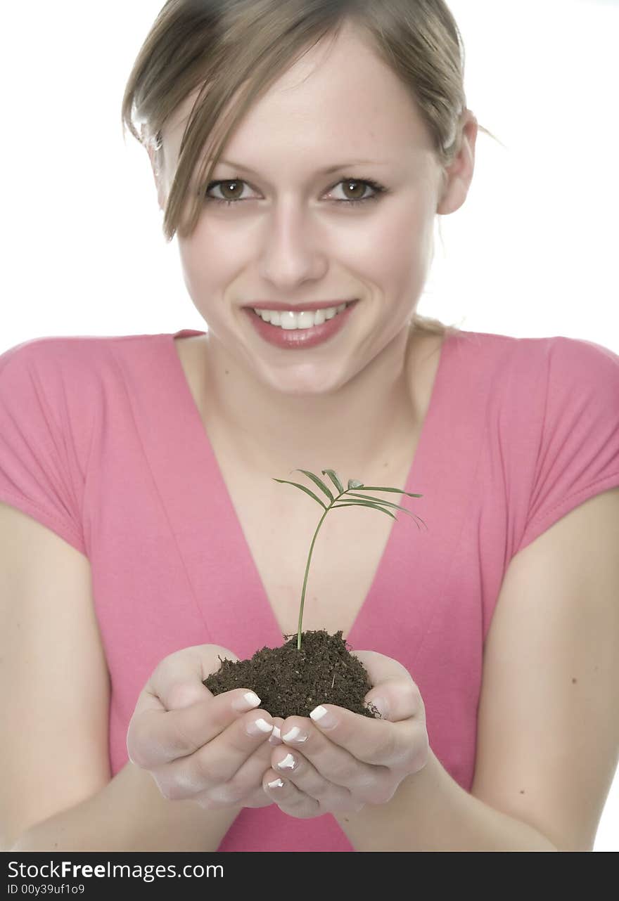 A pretty young woman holding a growing plant. A pretty young woman holding a growing plant