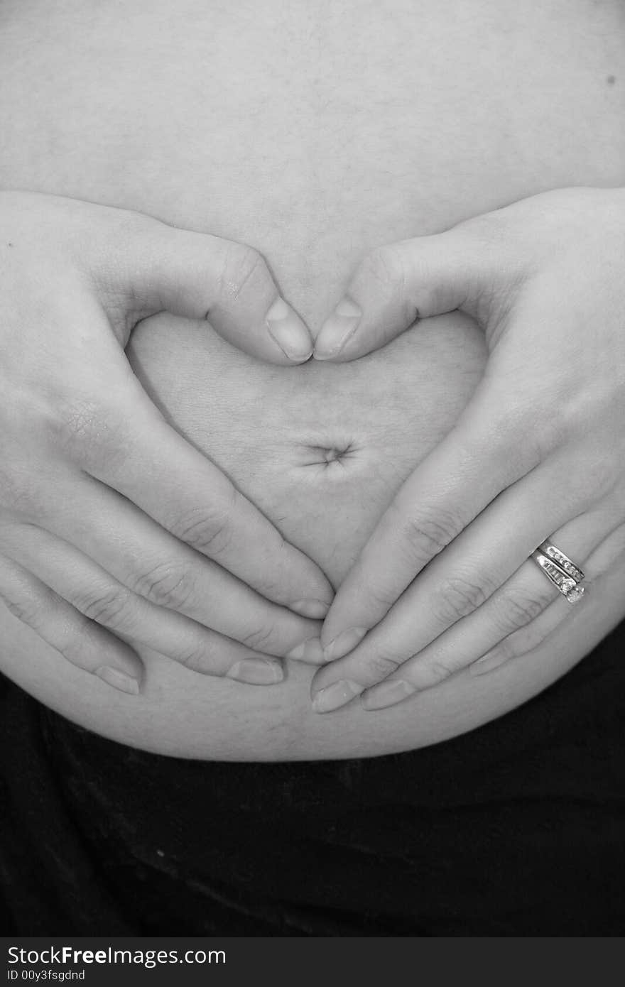 Hands forming heart on pregnant belly. Hands forming heart on pregnant belly