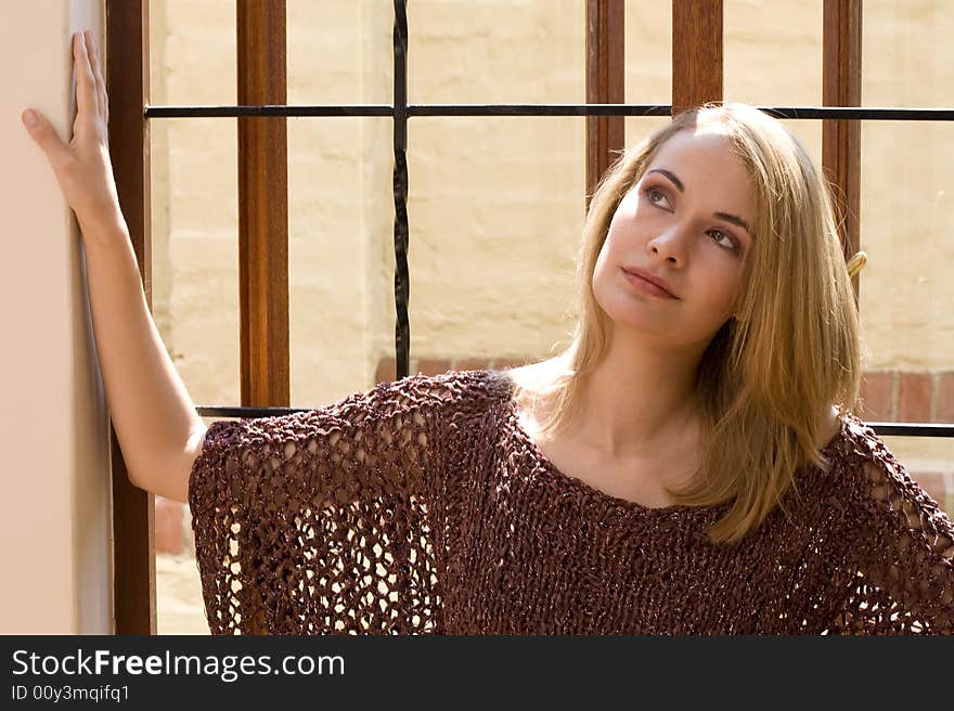 Blond girl sitting in the sun in windowsill thinking about the future. Blond girl sitting in the sun in windowsill thinking about the future