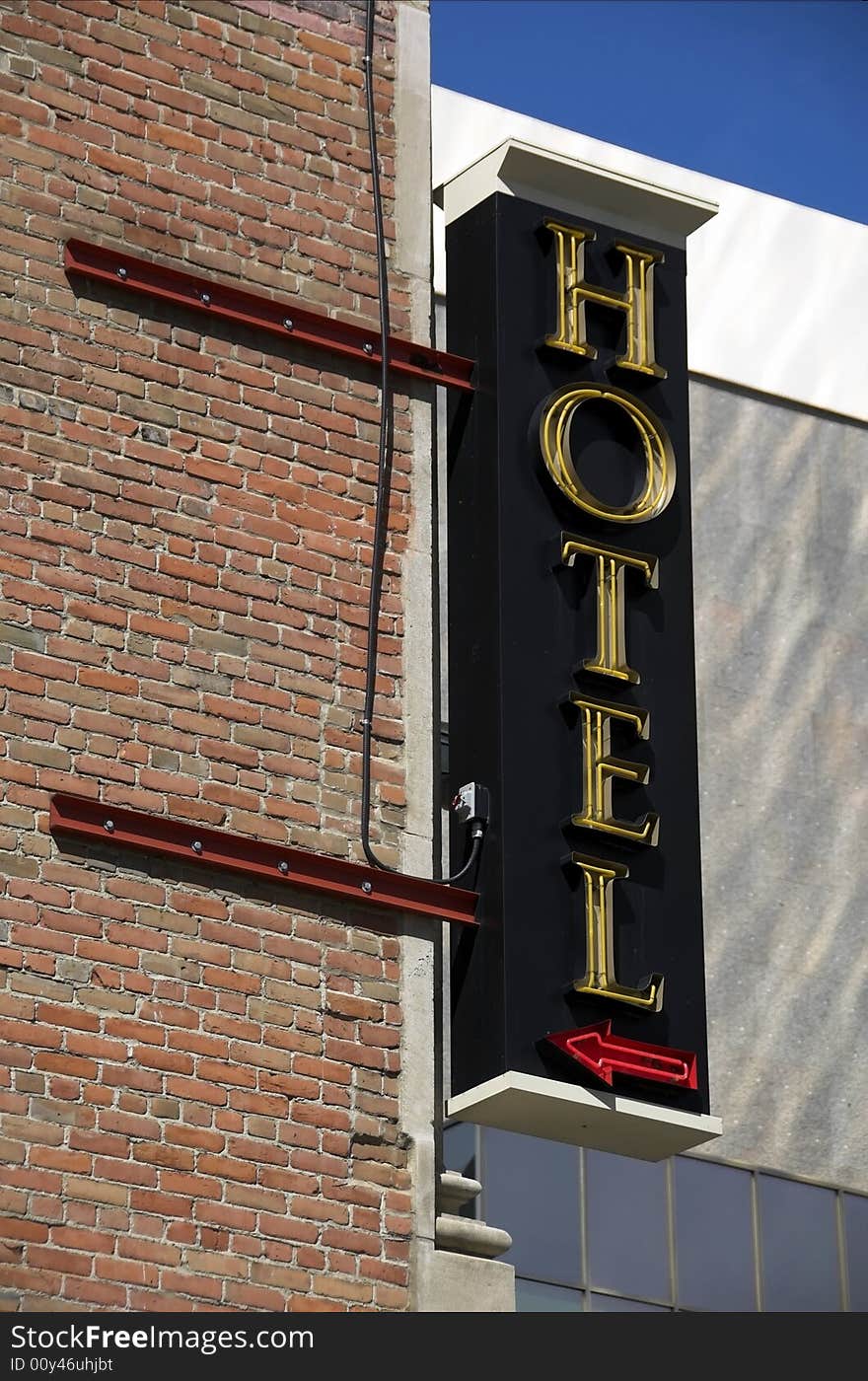 A neon sign for a hotel sticks out of a corner building. A neon sign for a hotel sticks out of a corner building.