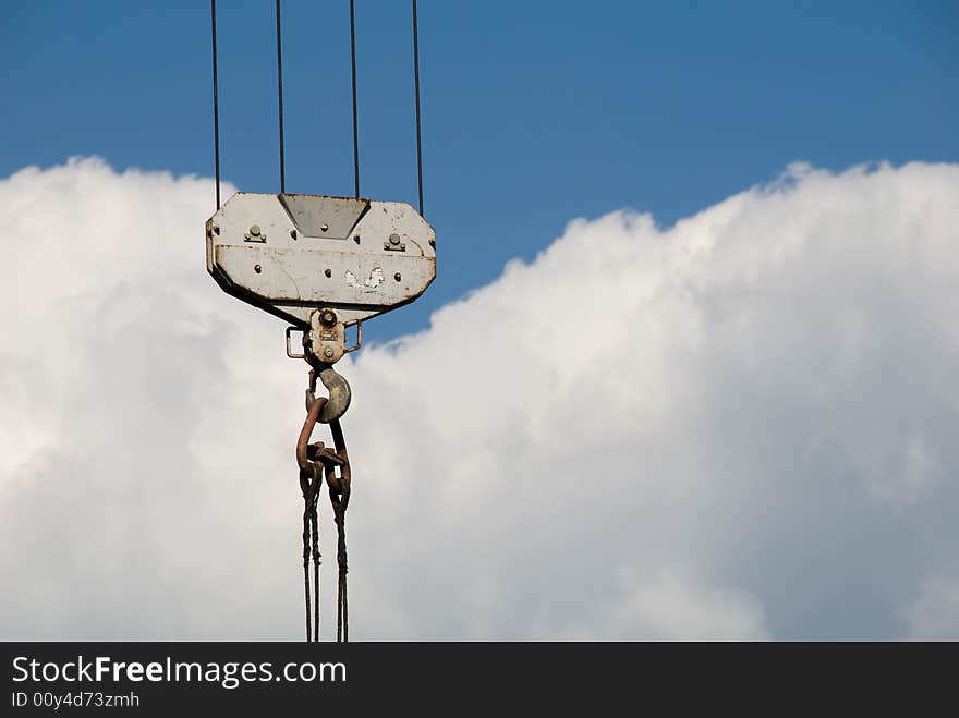 Crane hook with ropes against clouds sky background