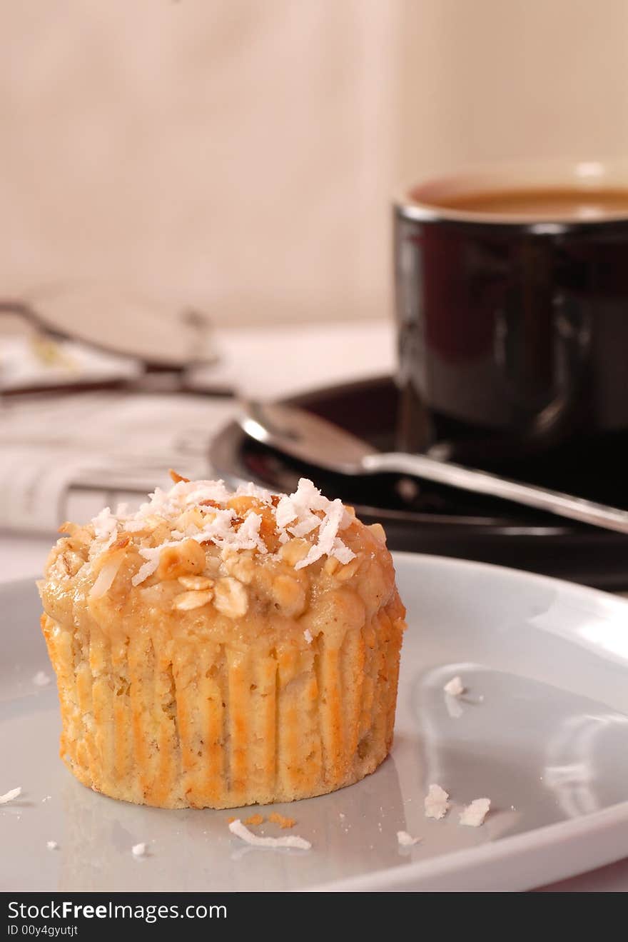 Freshly baked tropical pineapple, coconut and nut muffin with coffee and the morning paper. Freshly baked tropical pineapple, coconut and nut muffin with coffee and the morning paper