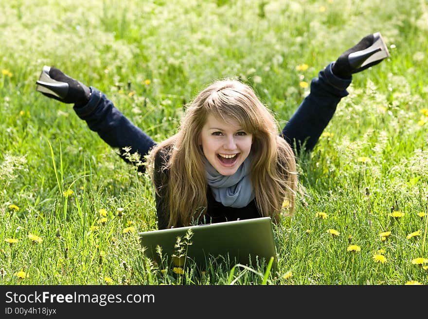 Nice young model with laptop on green grass background