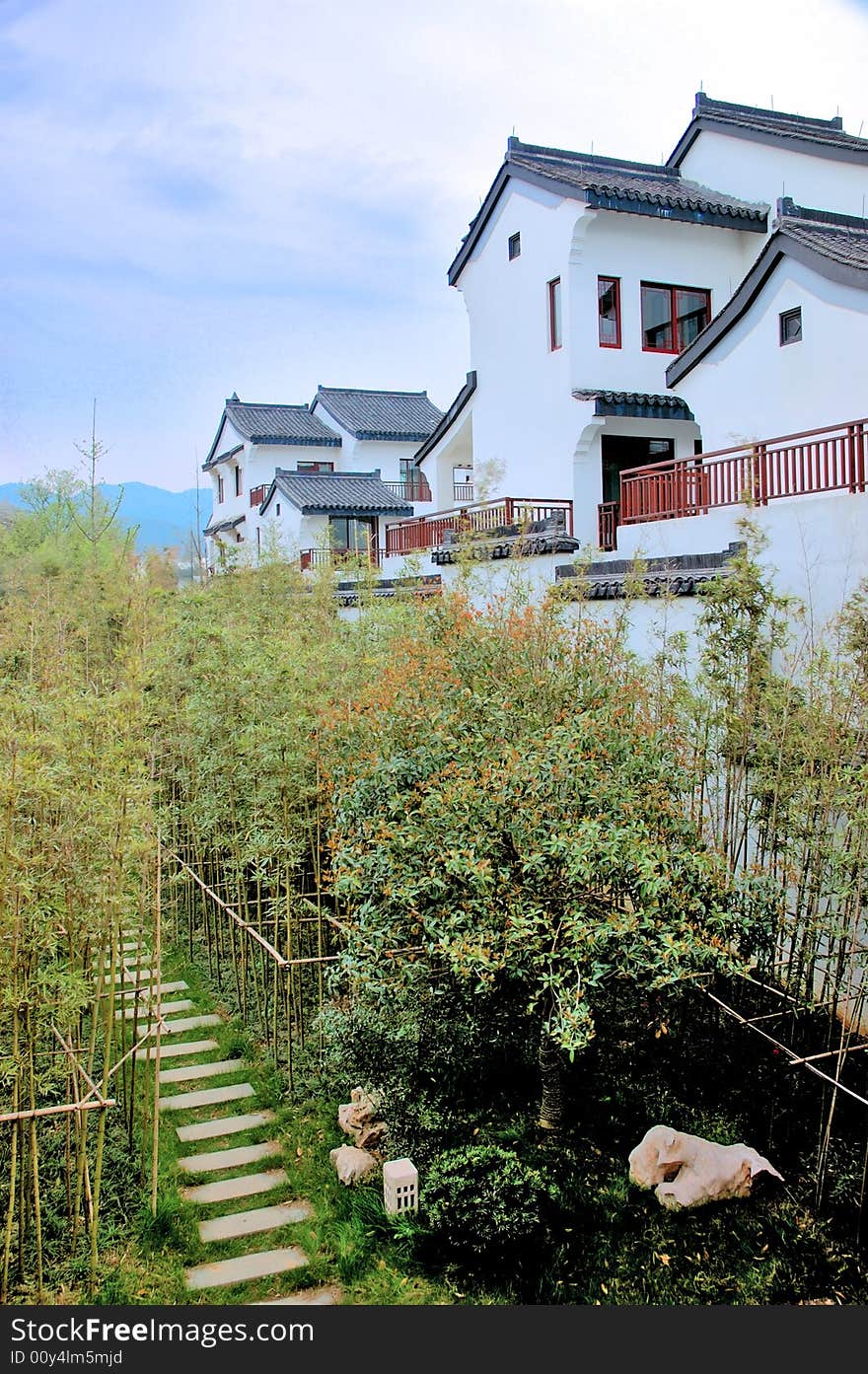 Chinese traditional house which is surrounded by bamboo. there is a litte way winding from the bamboo forest.