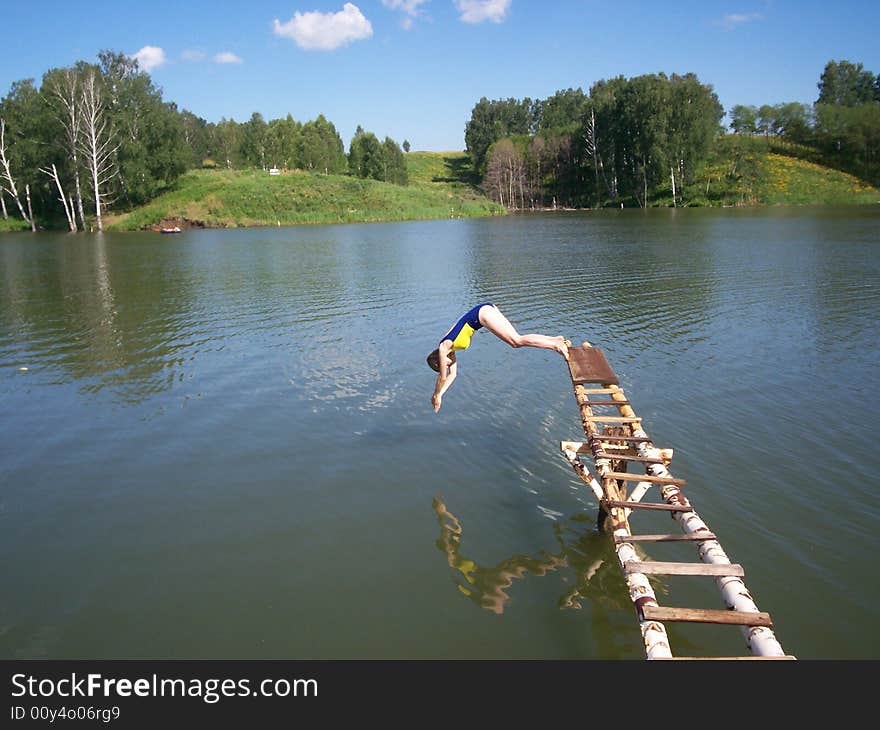 Woman is jumping into lake from footbridge. Woman is jumping into lake from footbridge.