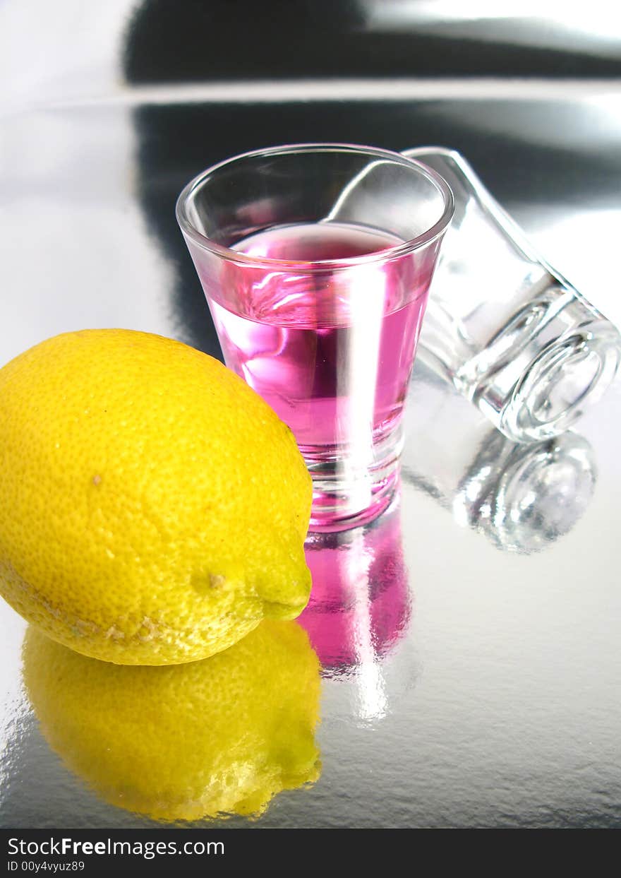 Cherry cocktail shot with a empty glass and a lemon on a silver background. Cherry cocktail shot with a empty glass and a lemon on a silver background