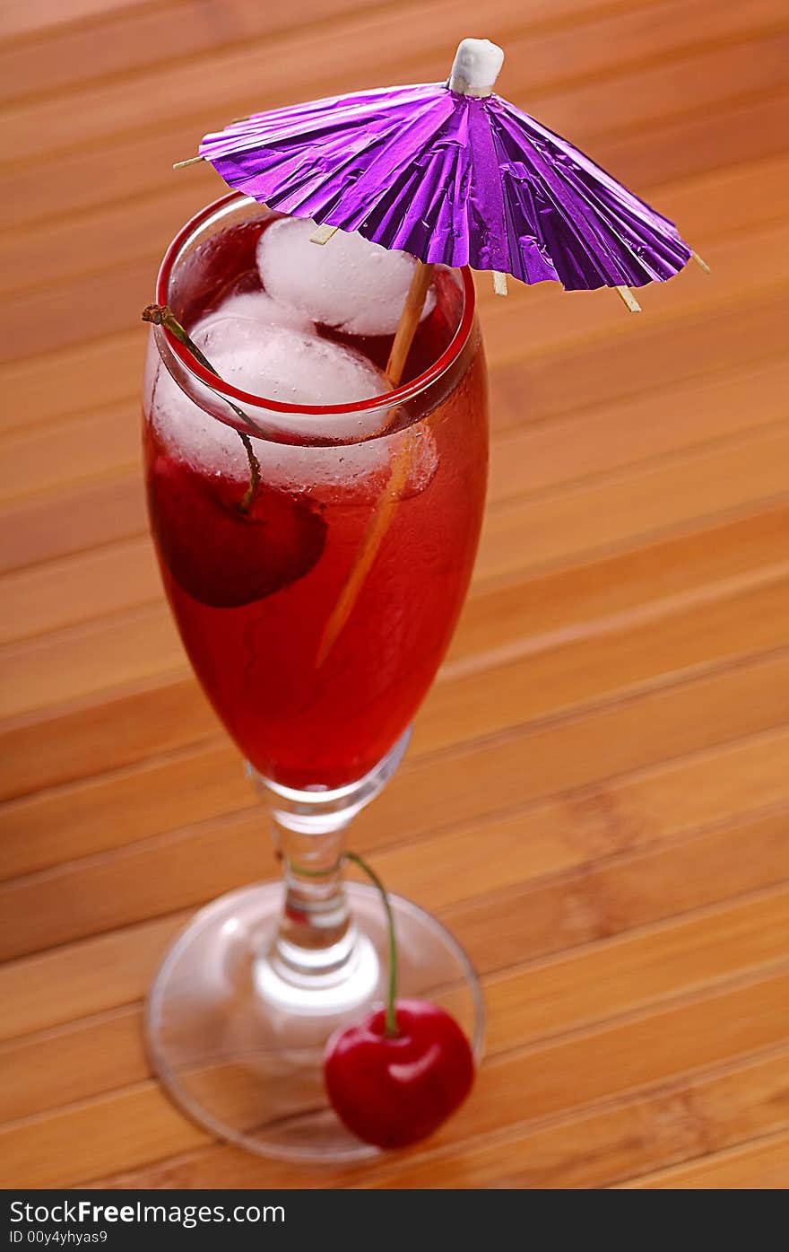 A red cocktail in a glass with cherry and ice. A red cocktail in a glass with cherry and ice