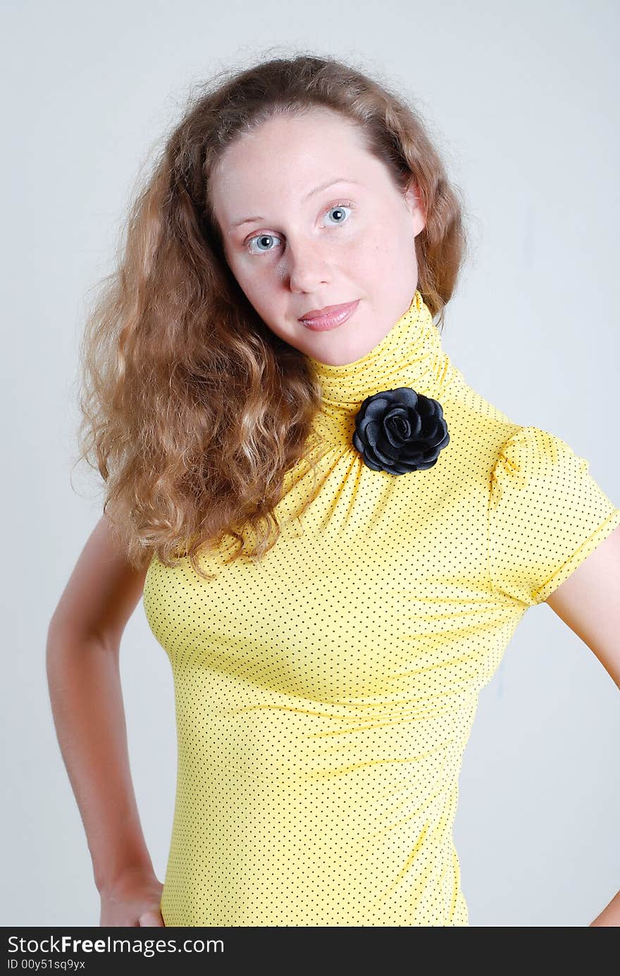 The girl in a yellow blouse with a black rose looks through a shoulder