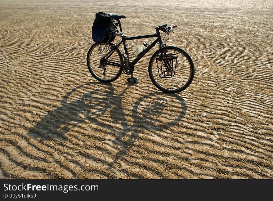 A black mountain bike in a desert. A black mountain bike in a desert