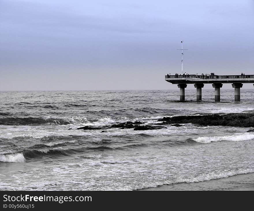 Black and white pier in stormy sea with blue sky. Black and white pier in stormy sea with blue sky