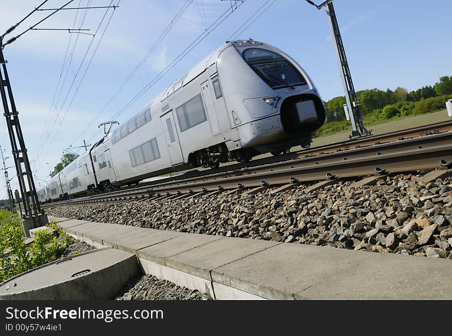 High-speed commuter-train on the move, surrounded by countryside and blue-sky. High-speed commuter-train on the move, surrounded by countryside and blue-sky