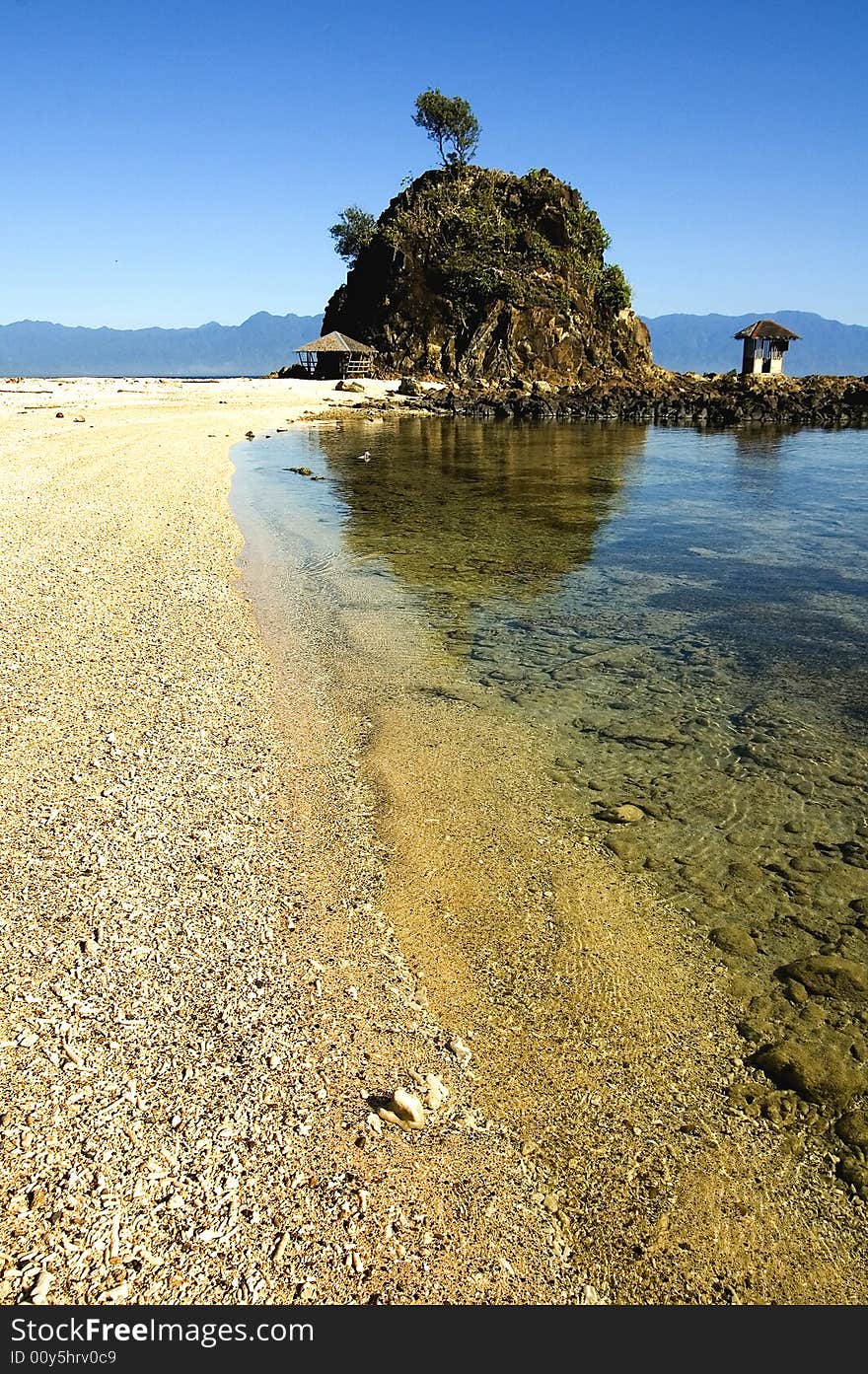 A sea shore with a clear water and small hils on the side.