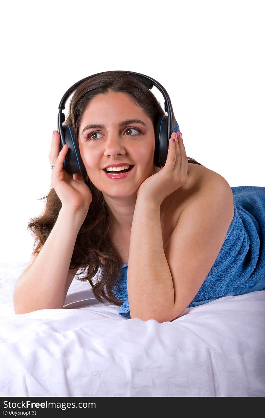 A beautiful girl, lying wrapped in a blue towel, wearing headphones, enjoying the music. A beautiful girl, lying wrapped in a blue towel, wearing headphones, enjoying the music