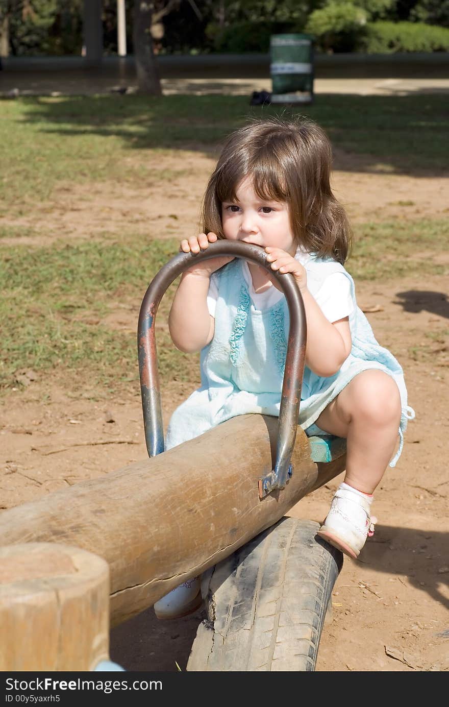 Adorable little girl playing on a see-saw. Vertically framed shot. Adorable little girl playing on a see-saw. Vertically framed shot.