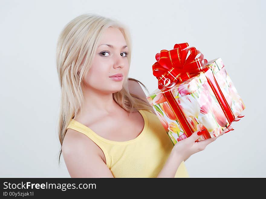 Smiling blond dressed in yellow shirt with big gift box in hands. Smiling blond dressed in yellow shirt with big gift box in hands