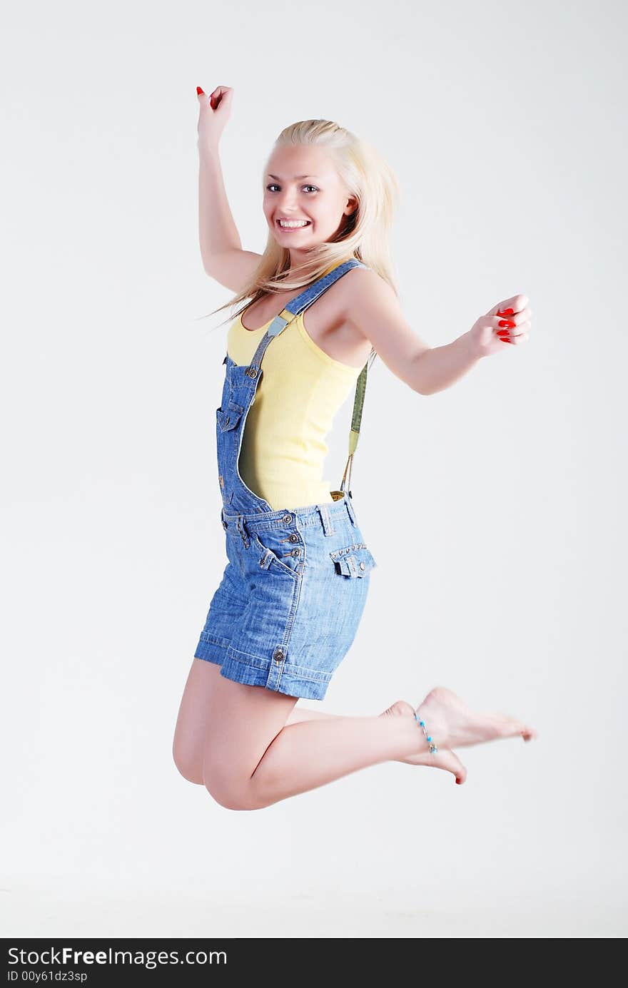 The beautiful young girl in a yellow vest and overalls. The beautiful young girl in a yellow vest and overalls