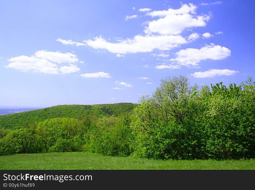 Green field and hills with blue sky and clouds. Green field and hills with blue sky and clouds