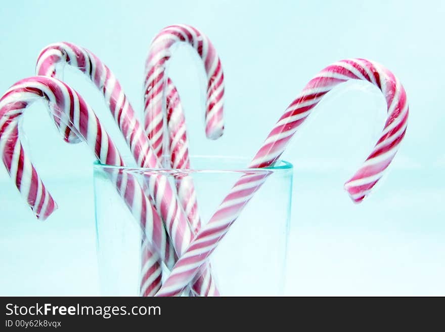 Red and white striped candy canes - or sticks of rock in the UK - isolated on a light blue background. Red and white striped candy canes - or sticks of rock in the UK - isolated on a light blue background.