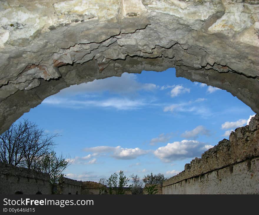 Arch of wall of an old building and blue sky with clouds