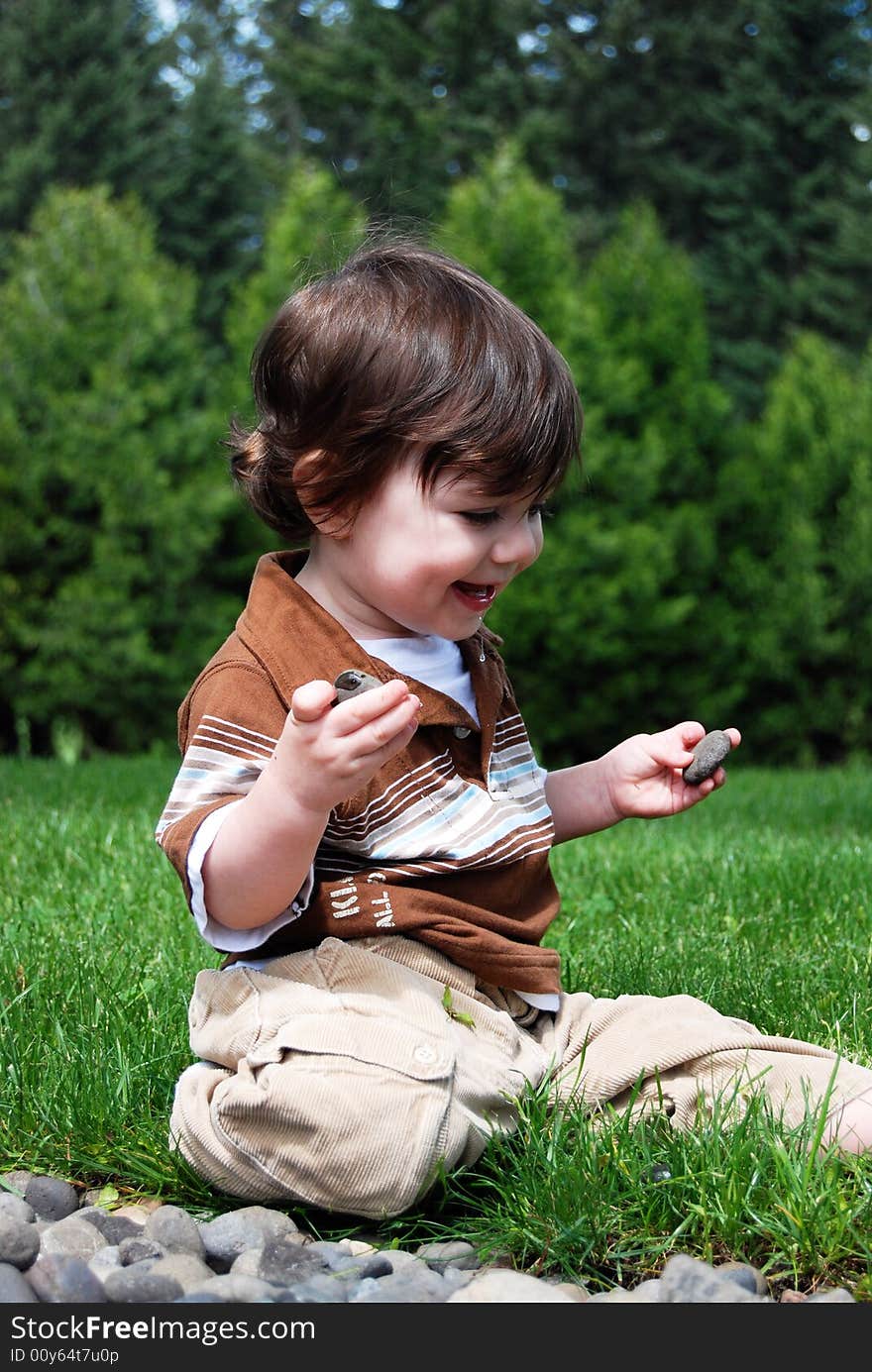 Adorable little boy playing in the grass outside on a hot summer day. Vertically framed shot. Adorable little boy playing in the grass outside on a hot summer day. Vertically framed shot.