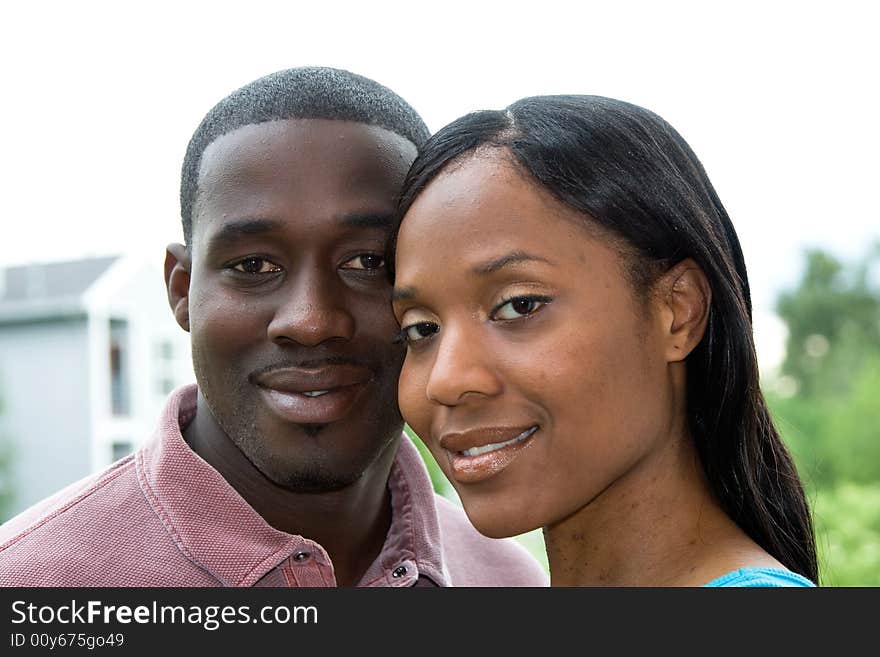 Attractive smiling young couple, looking at the camera, in a close-up embrace. Horizontally framed portrait shot. Attractive smiling young couple, looking at the camera, in a close-up embrace. Horizontally framed portrait shot.