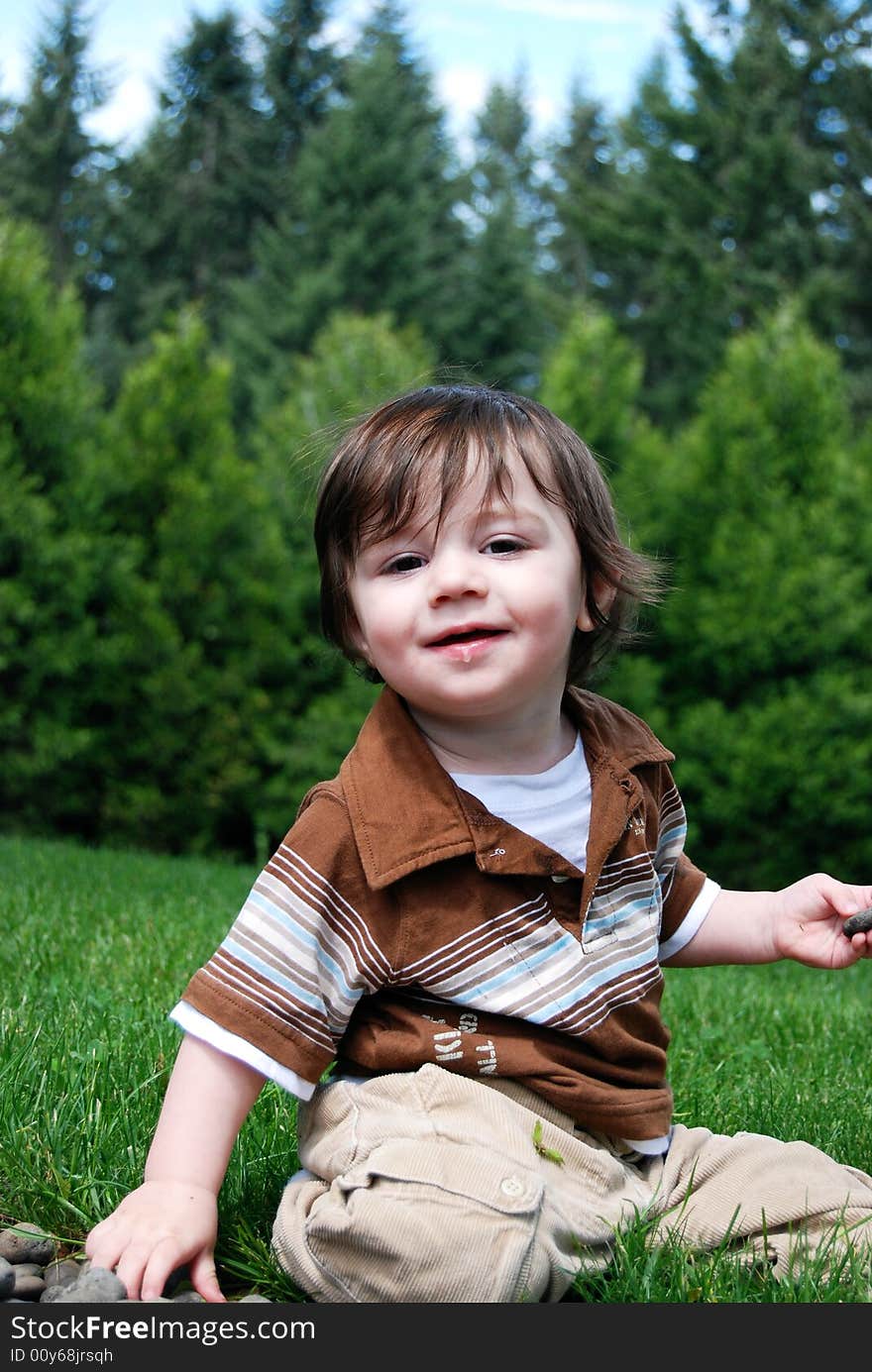 Adorable little boy playing in the grass outside on a hot summer day. Vertically framed shot. Adorable little boy playing in the grass outside on a hot summer day. Vertically framed shot.