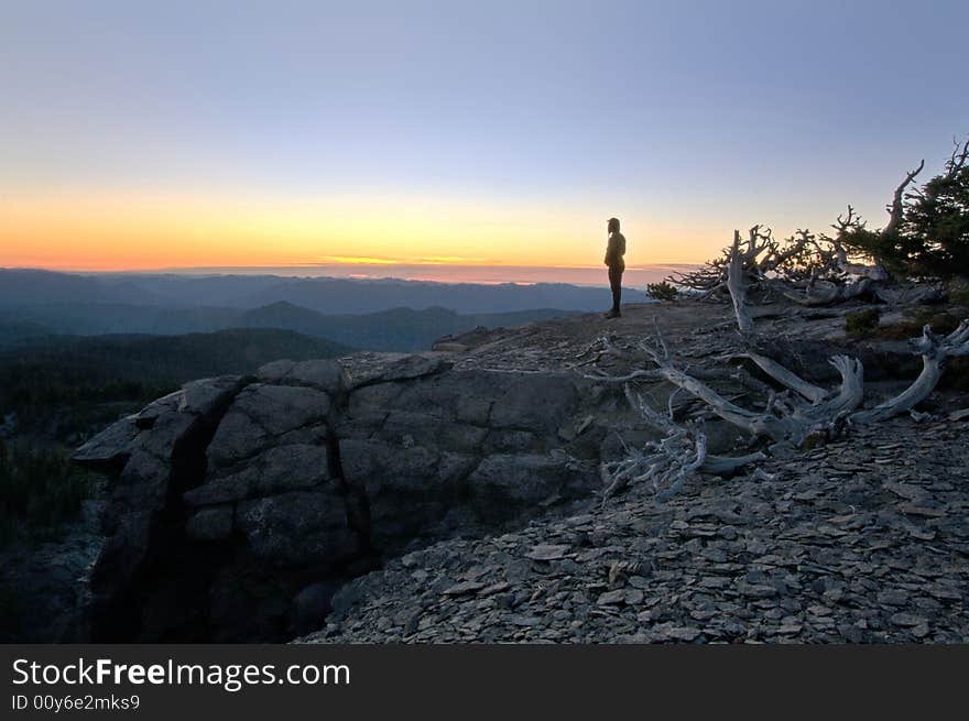 Woman watching the sunset from a rock bluff. Woman watching the sunset from a rock bluff