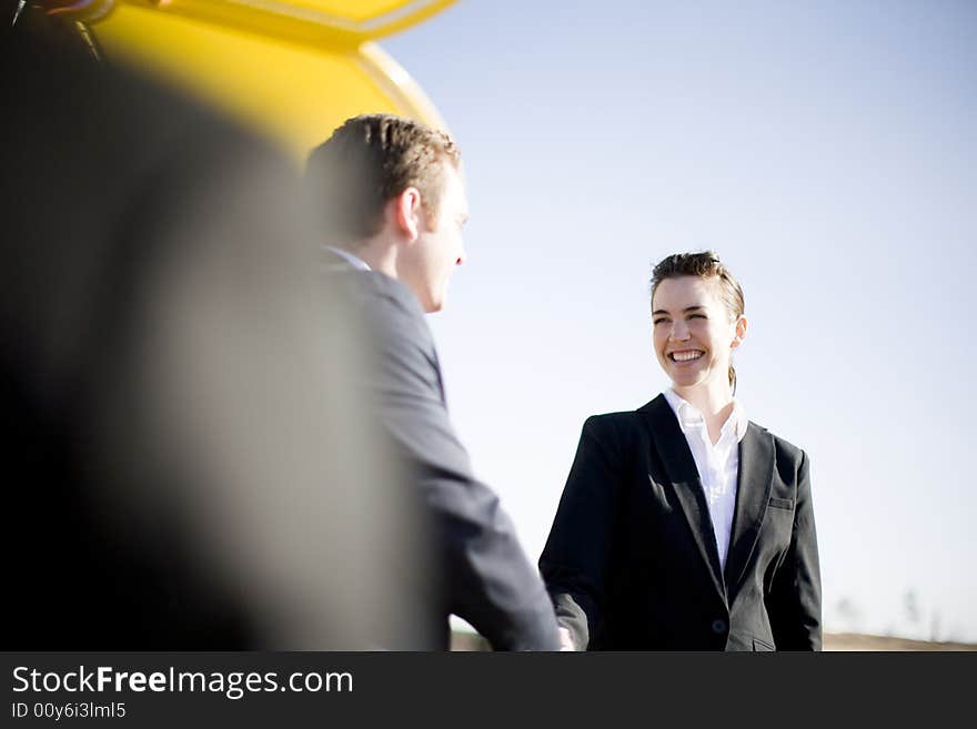 Businessman and businesswoman standing shaking hands wearing formal business attire. Businessman and businesswoman standing shaking hands wearing formal business attire