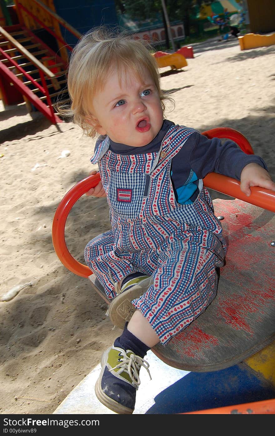 Sweet baby on merry-go-round having fun on the playground