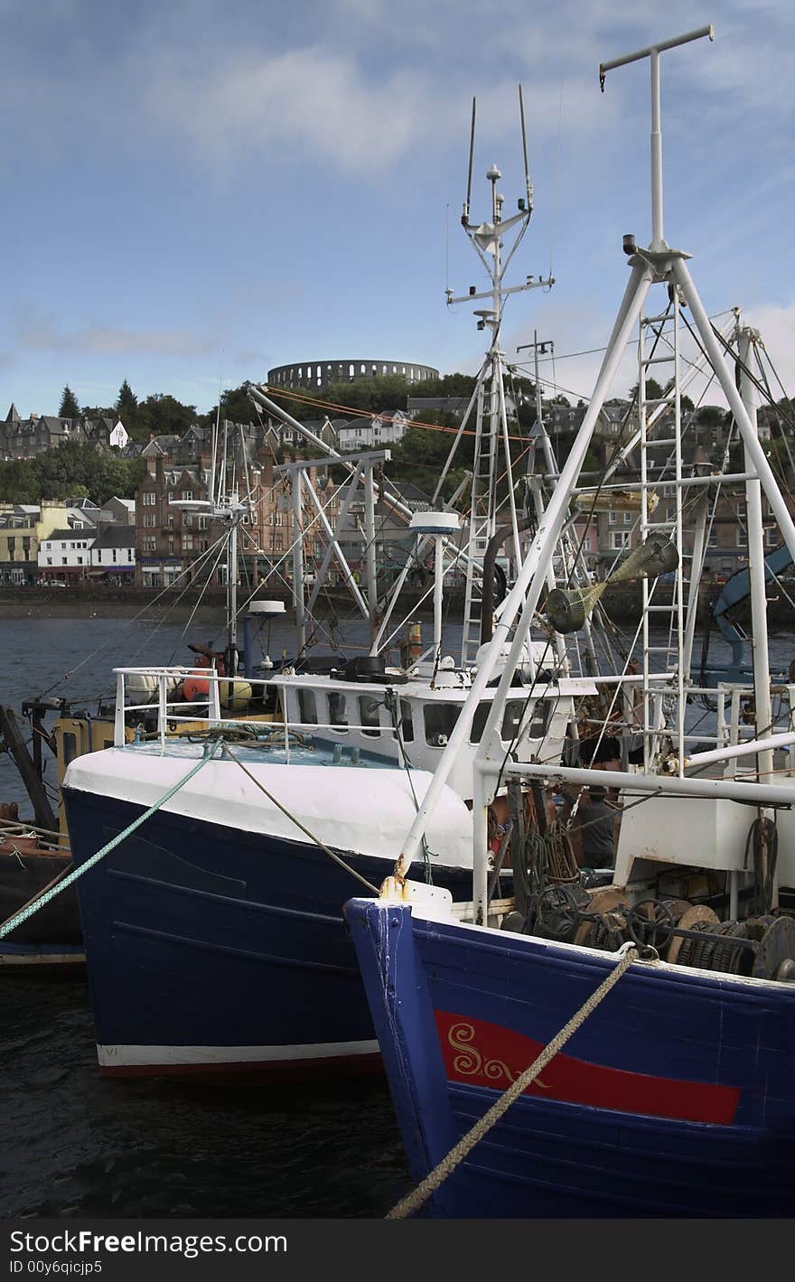 Oban harbour with fishing boats at the quayside and with McCaigs tower in the distance. Oban harbour with fishing boats at the quayside and with McCaigs tower in the distance