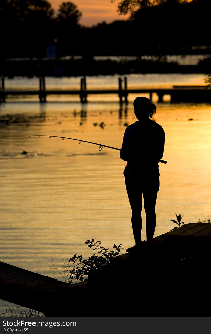 Women fishing on shoreline at dusk during a sunrise. Women fishing on shoreline at dusk during a sunrise.