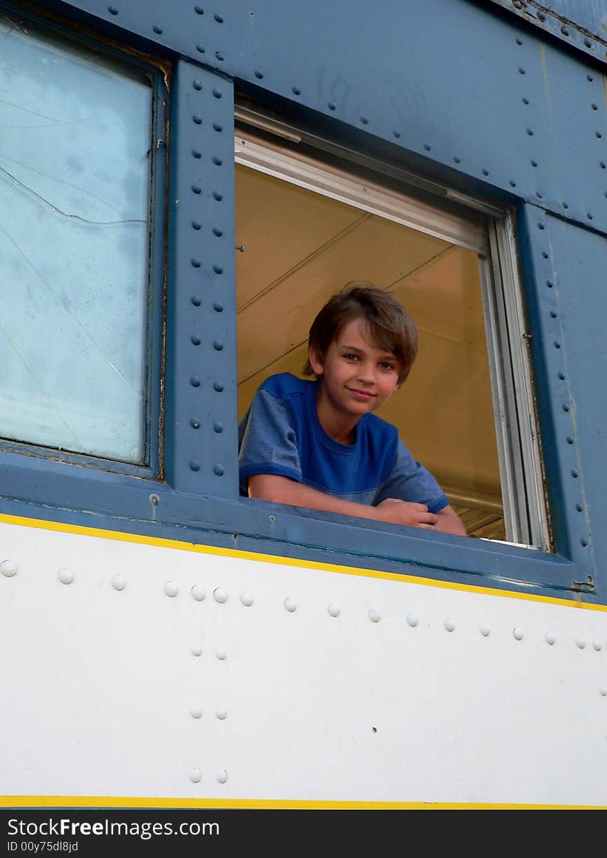 Boy in blue t-shirt in blue train leaning out the window; very handsome. Boy in blue t-shirt in blue train leaning out the window; very handsome