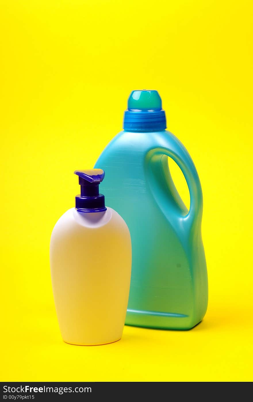 Cleaning supplies on yellow background including several spray bottles of chemicals