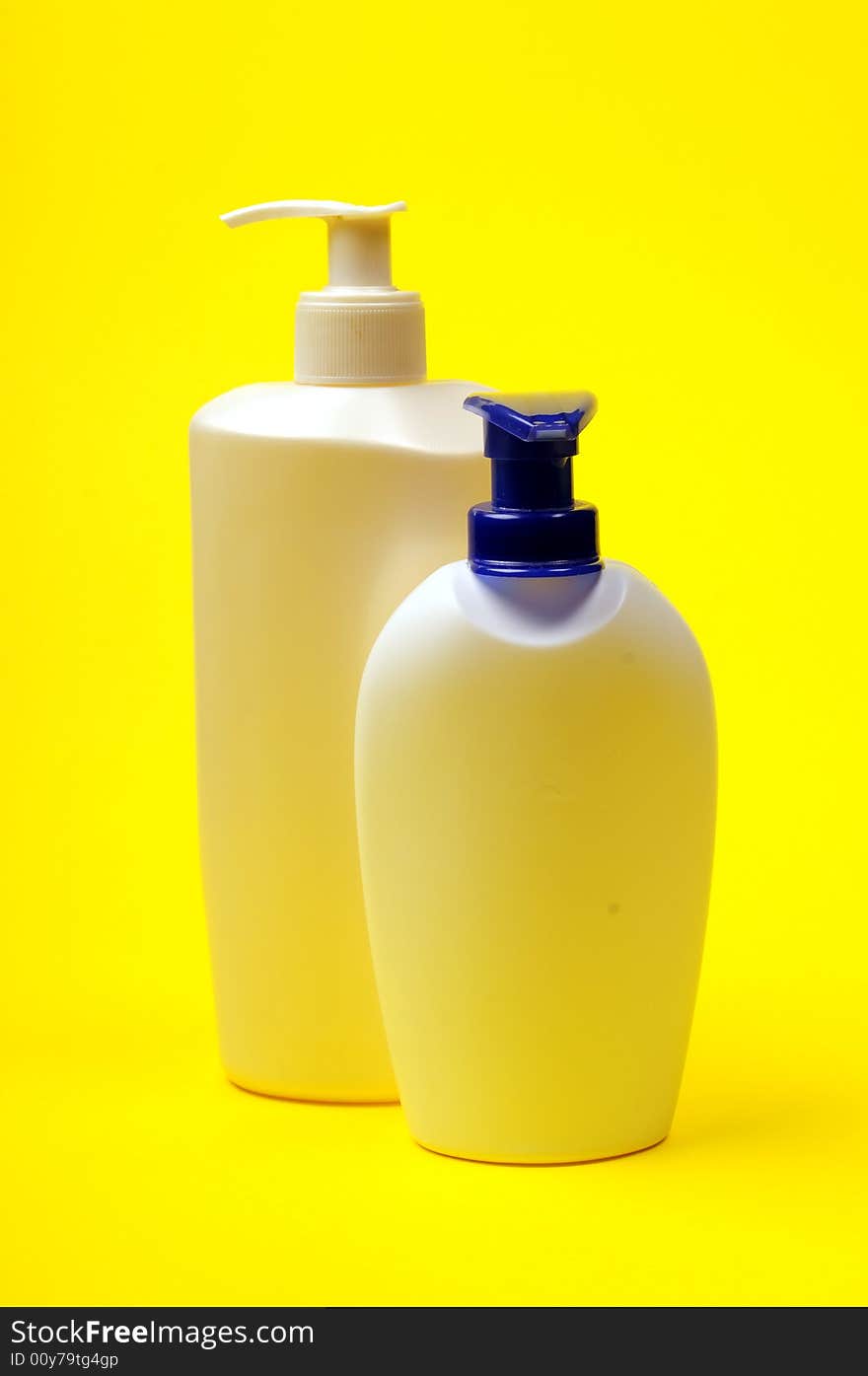 Cleaning supplies on yellow background including several spray bottles of chemicals