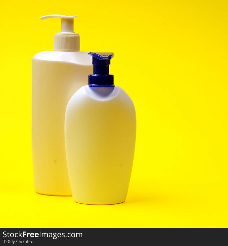 Cleaning supplies on yellow background including several spray bottles of chemicals