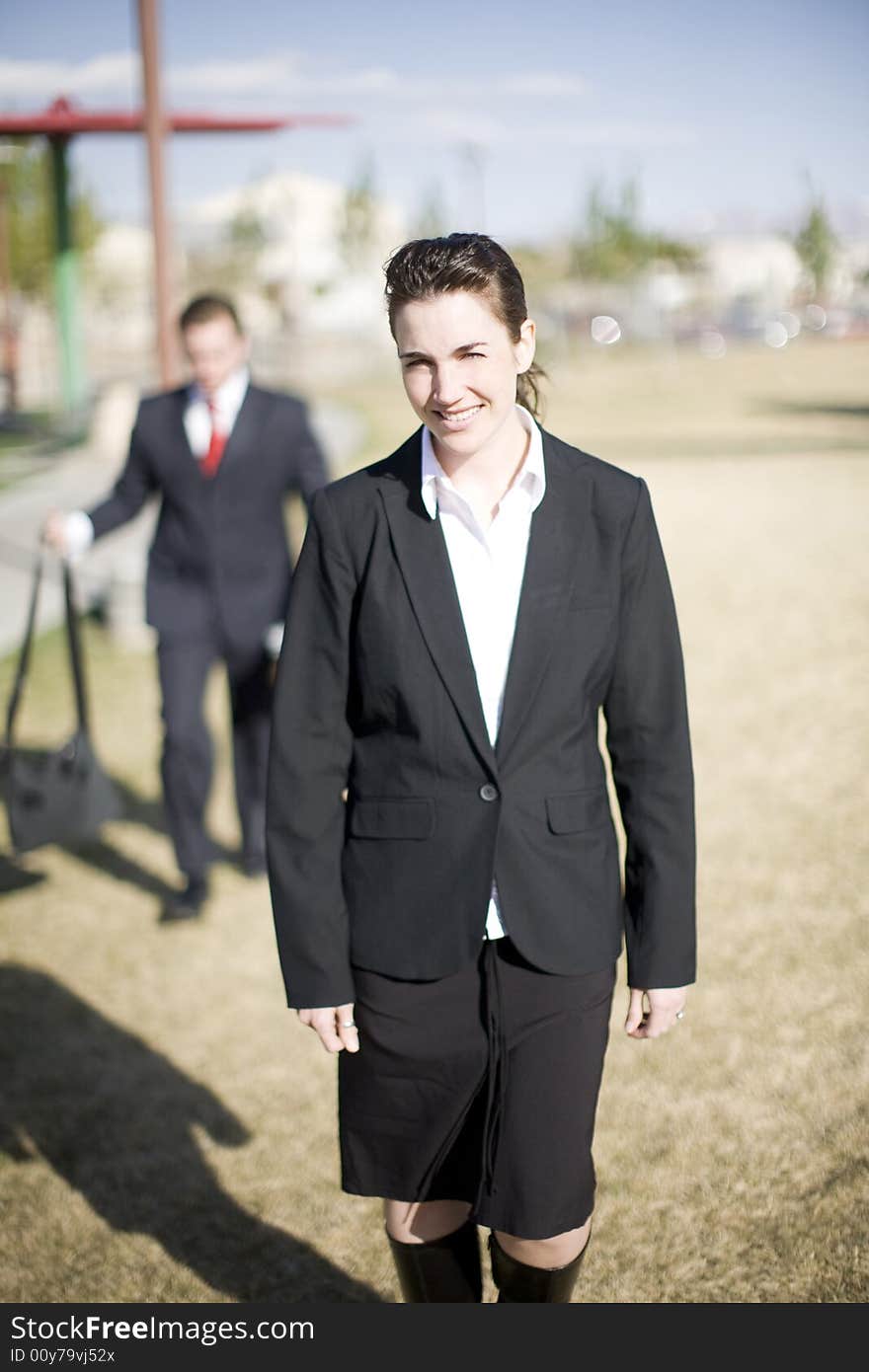 Front view of businessman and businesswoman dressed formally walking in same direction. Front view of businessman and businesswoman dressed formally walking in same direction