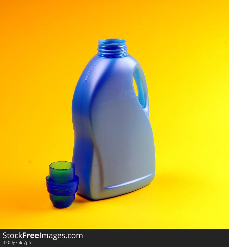 Cleaning supplies on yellow background including several spray bottles of chemicals