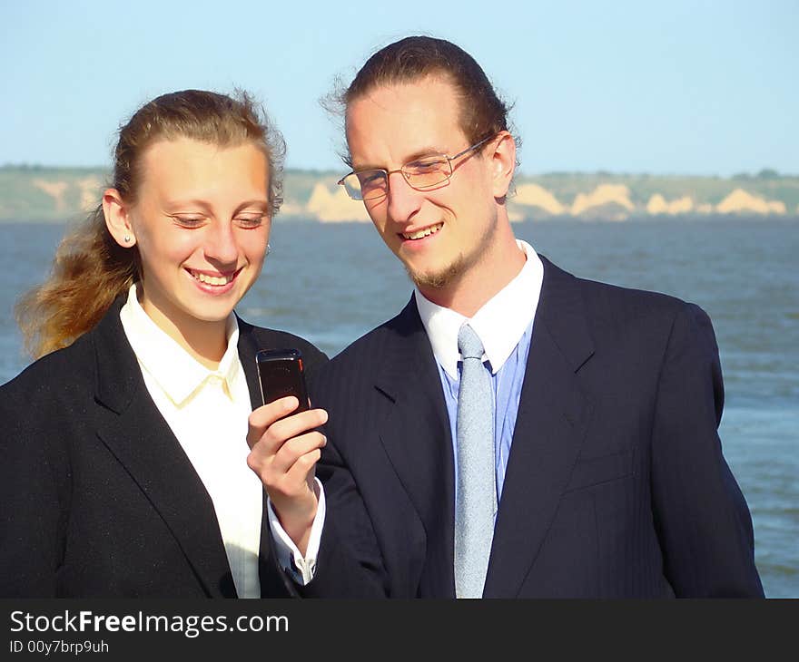 Young business man with mobile telephone and smiling girl. Rest and teaching. Young business man with mobile telephone and smiling girl. Rest and teaching.