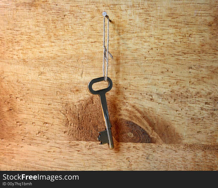 Old key hanging with cotton rope on wooden wall. Old key hanging with cotton rope on wooden wall