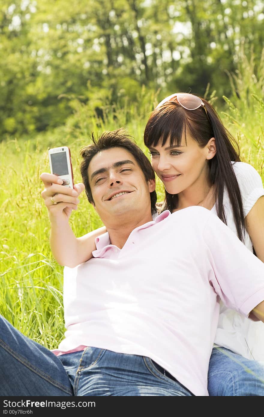 Young couple outdoors, woman taking photo with mobile phone. Young couple outdoors, woman taking photo with mobile phone