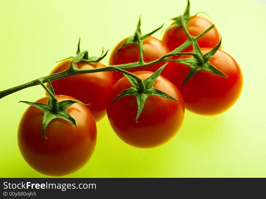 Branch of cherry tomatoes on a green background