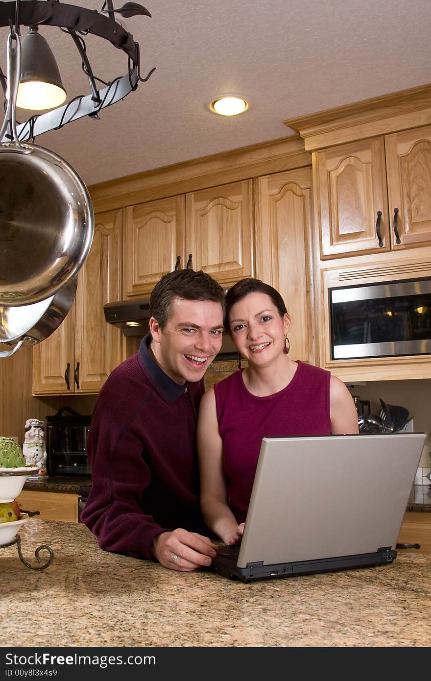 Couple With Laptop In Kitchen - Vertical