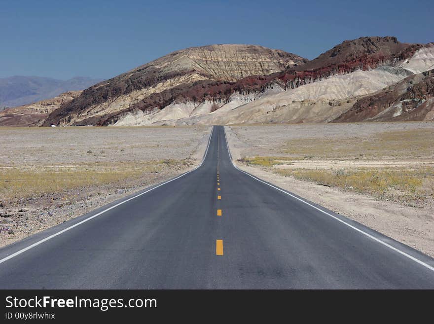 Road going to lowest part of Death Valley. Interstate road against geological feature. California. USA. Road going to lowest part of Death Valley. Interstate road against geological feature. California. USA