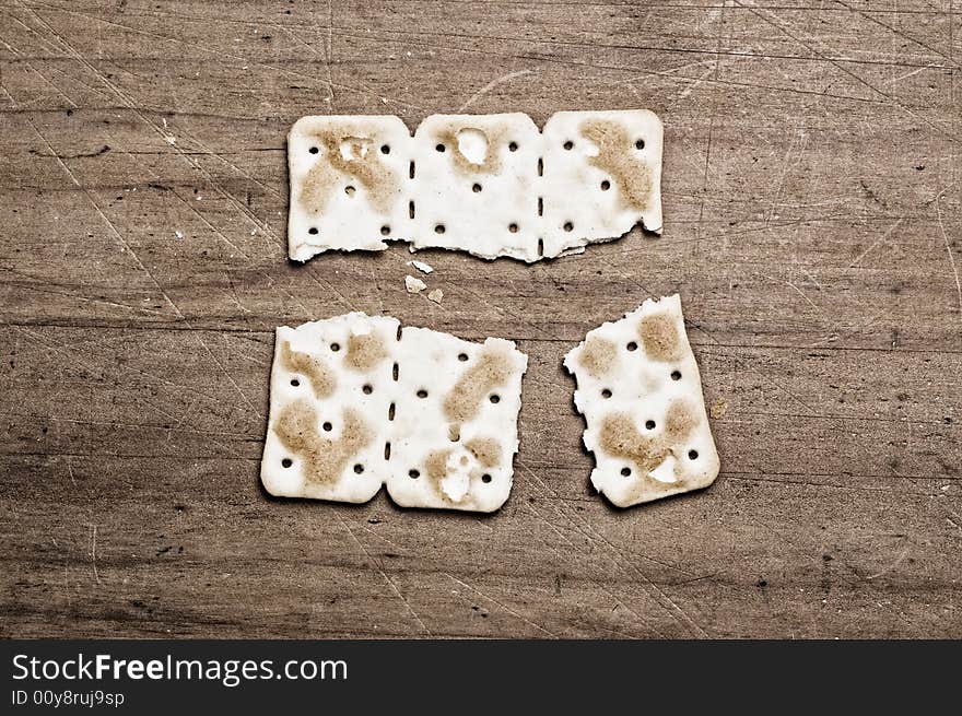 Broken cracker on a wooden surface. Broken cracker on a wooden surface.