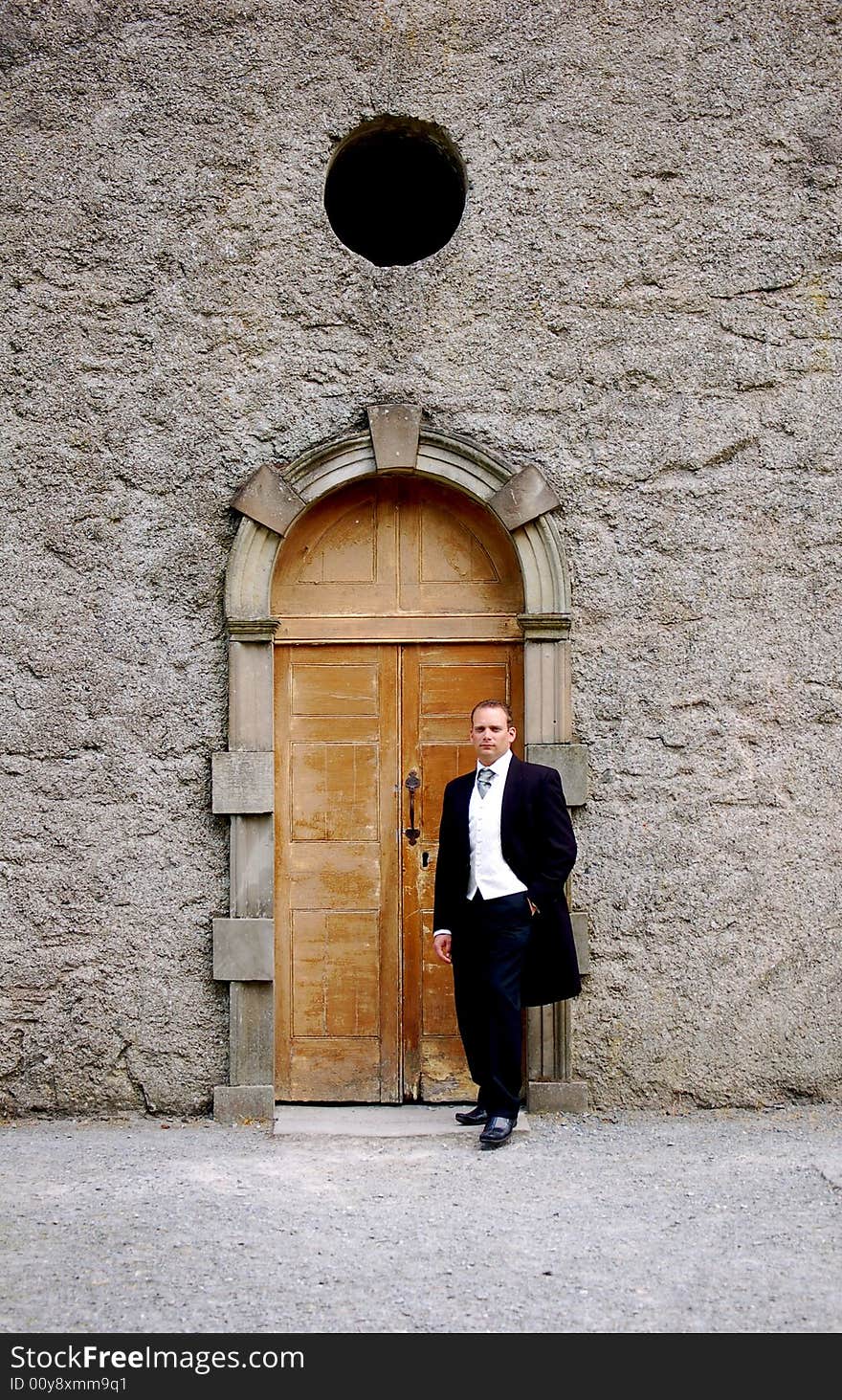 A solo groomsman waiting at the entrance of the church for his bride. A solo groomsman waiting at the entrance of the church for his bride